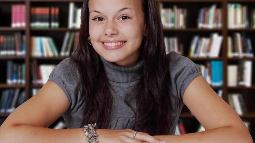 Ein junge Frau vor einer Regalreihe mit Büchern.