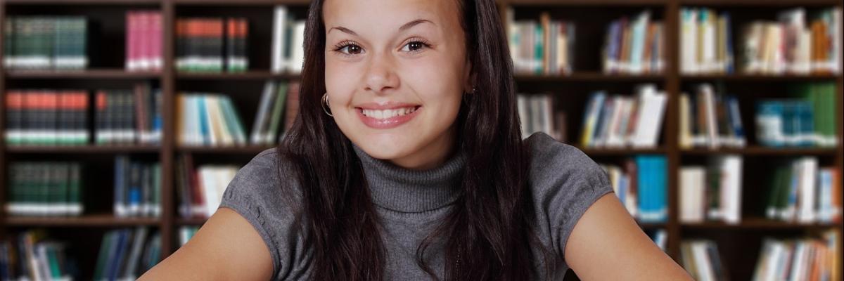 Ein junge Frau vor einer Regalreihe mit Büchern.