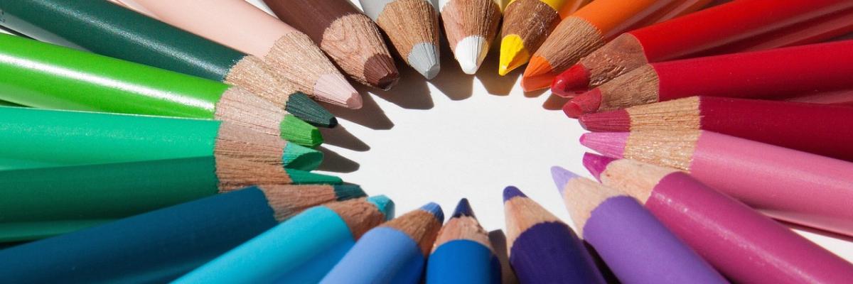 Verschiedenfarbige Bundstifte sind auf einem weißen Untergrund kreisförmig angeordnet. Die Spitzen zeigen nach innen und bilden einen Kreis.